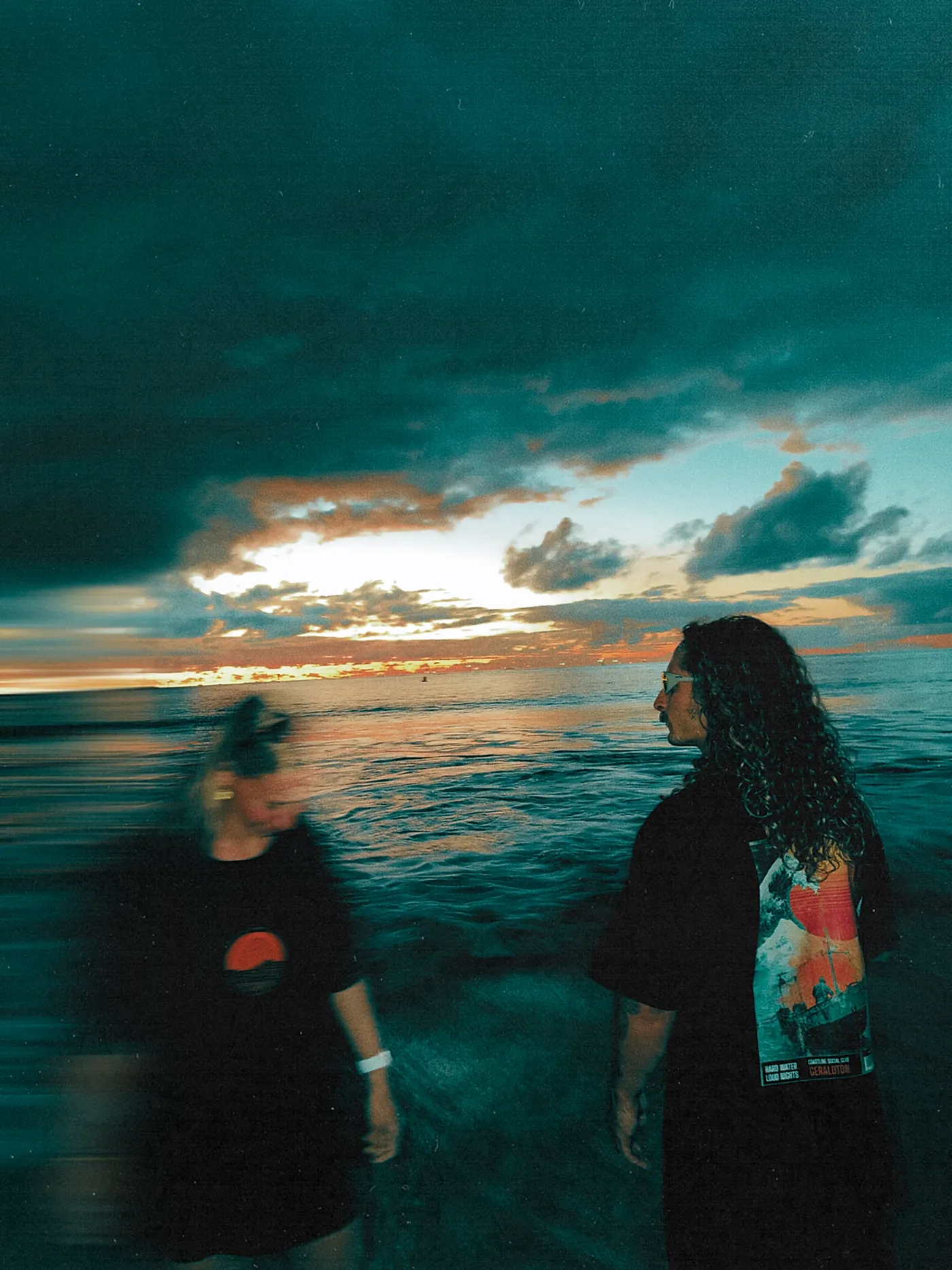 The same pair walking, the back print of the tee visible.